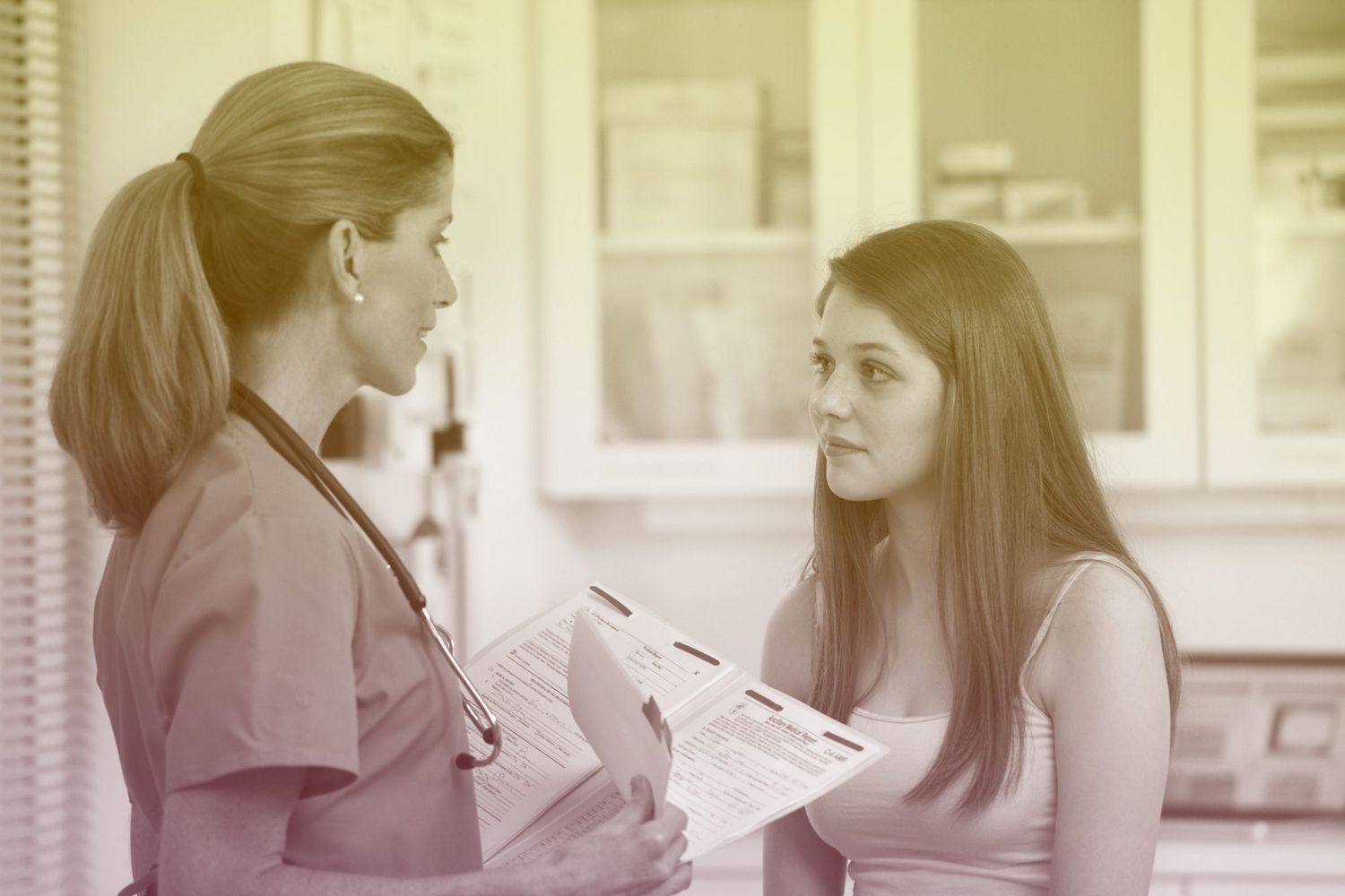 Doctor talking to teenage patient in examination room