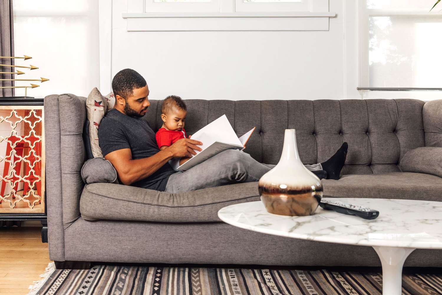 African American father reading to his baby on couch