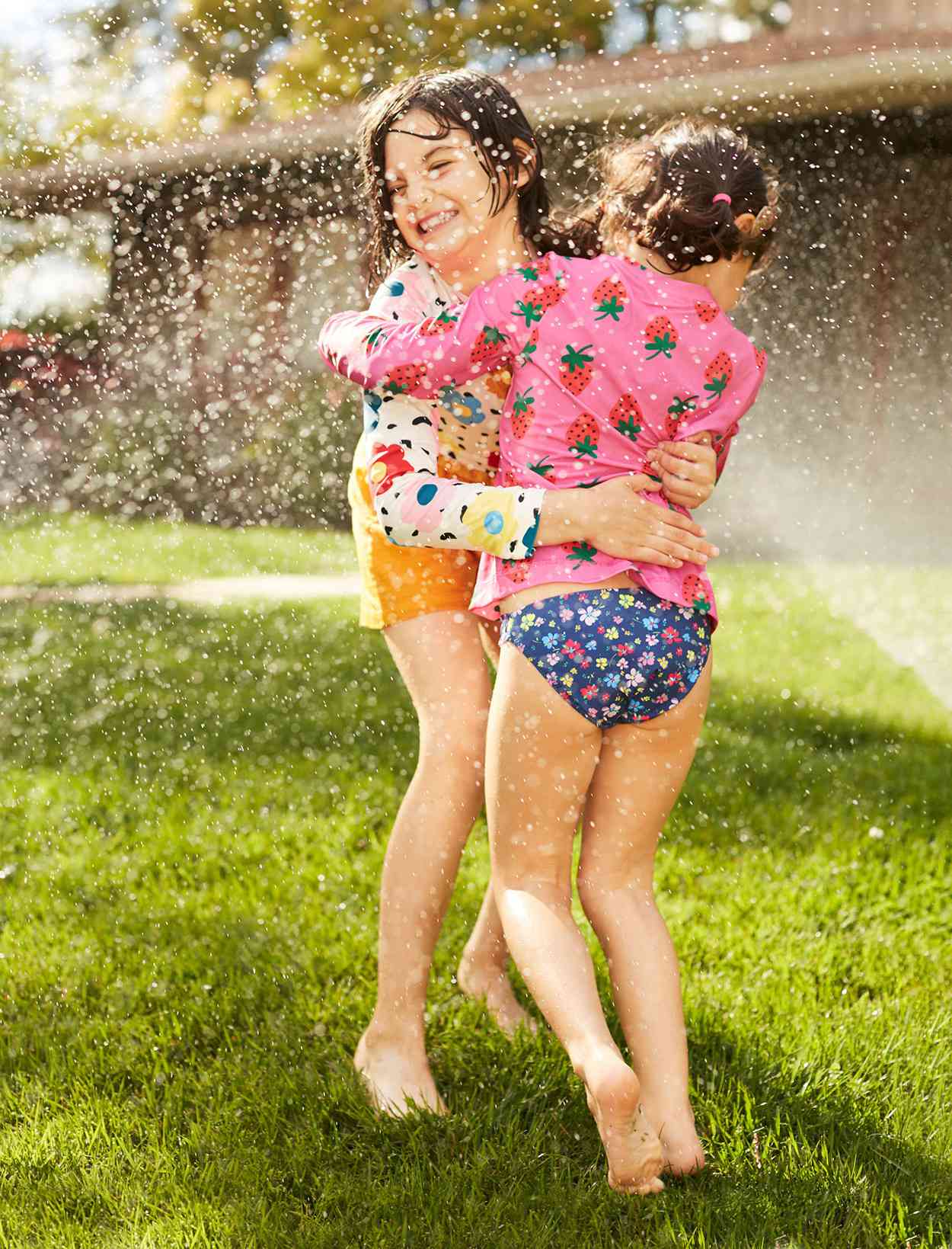 sisters hugging under sprinkler