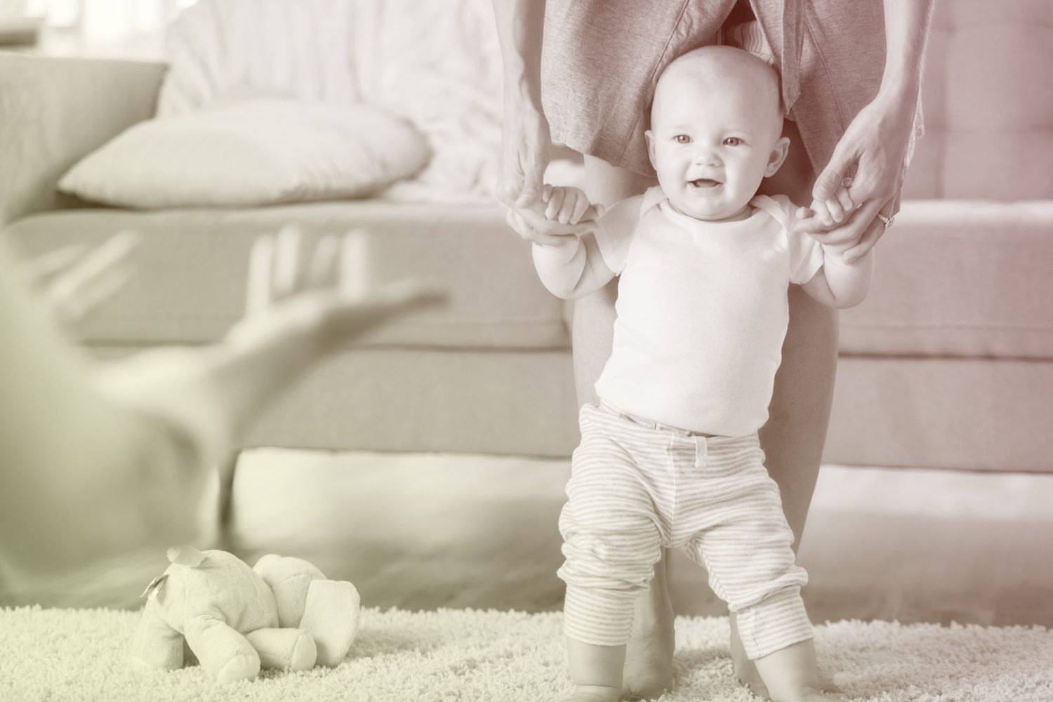 Baby being taught how to walk by parents