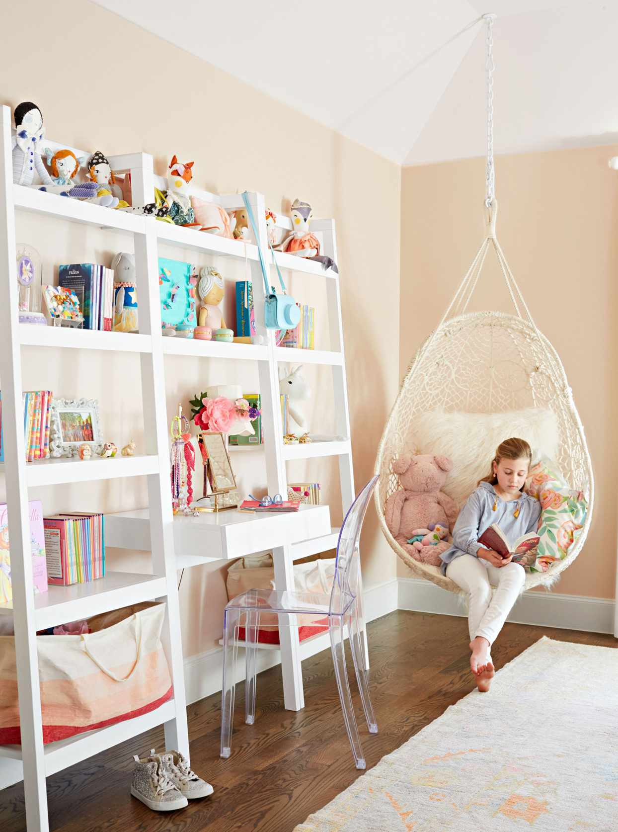 girl reading in white chair suspended from ceiling