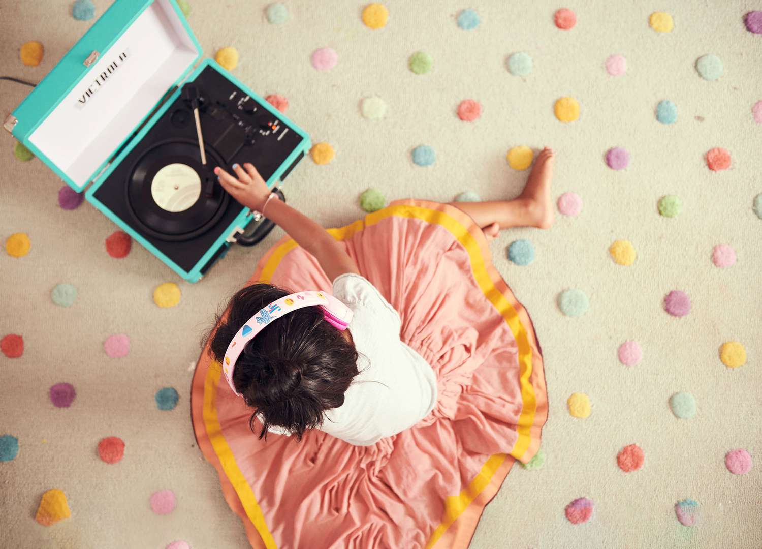 Child on polka dot carpet listening to record player