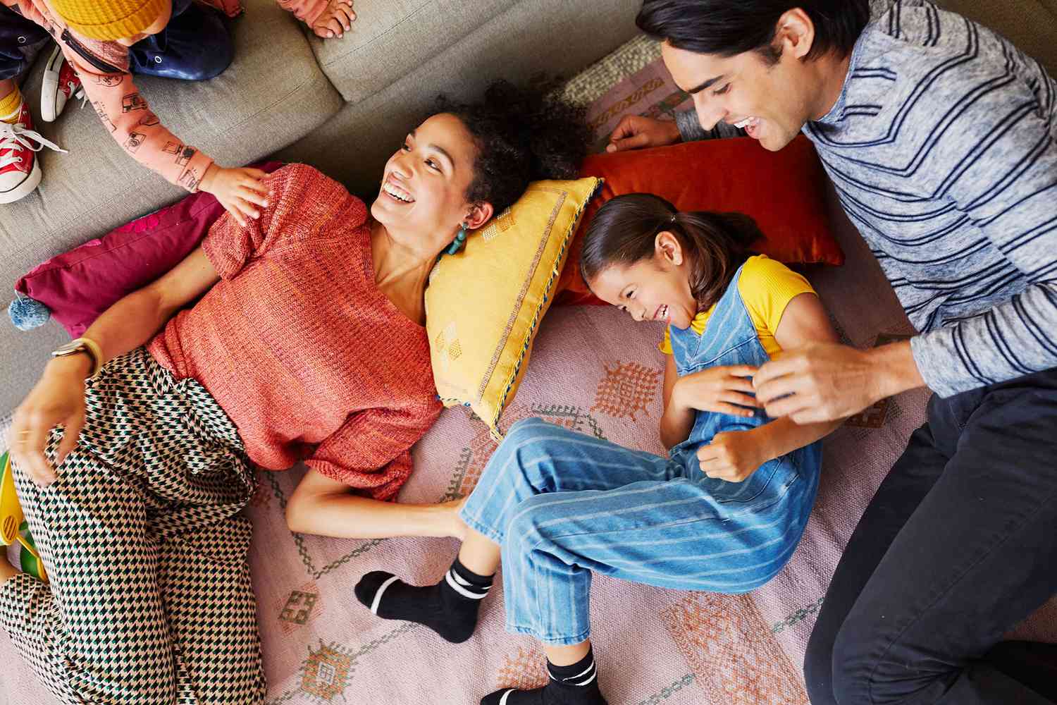 family lying on the floor giggling around pillows