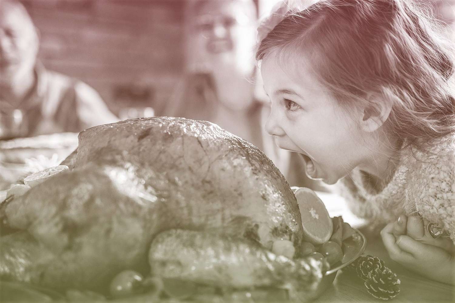 young girl about to bite into turkey during Thanksgiving dinner