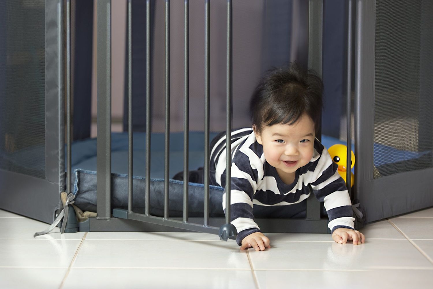 Asian toddler boy escaping from play pen.