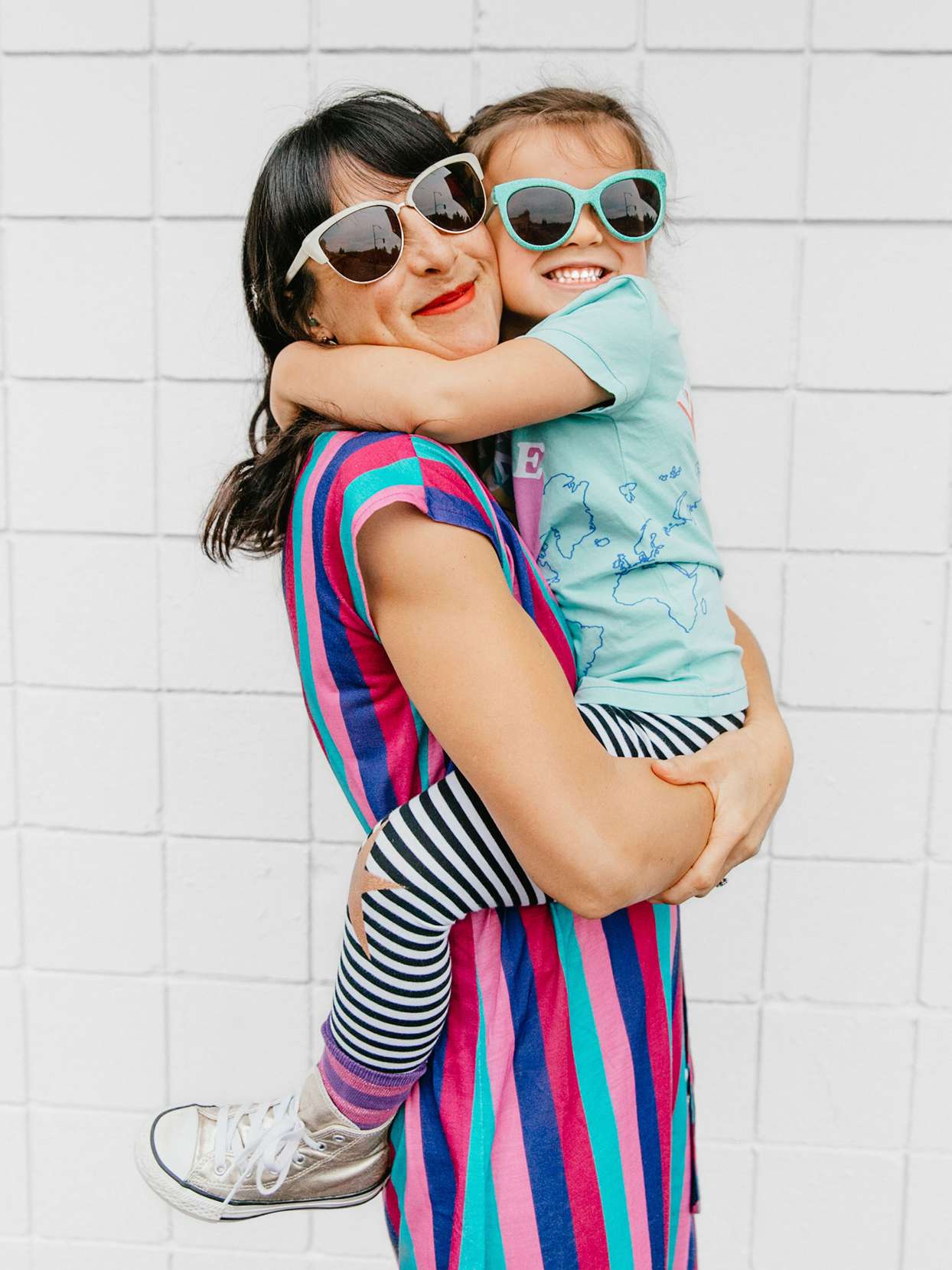 mom holding daughter both smiling and wearing sunglasses