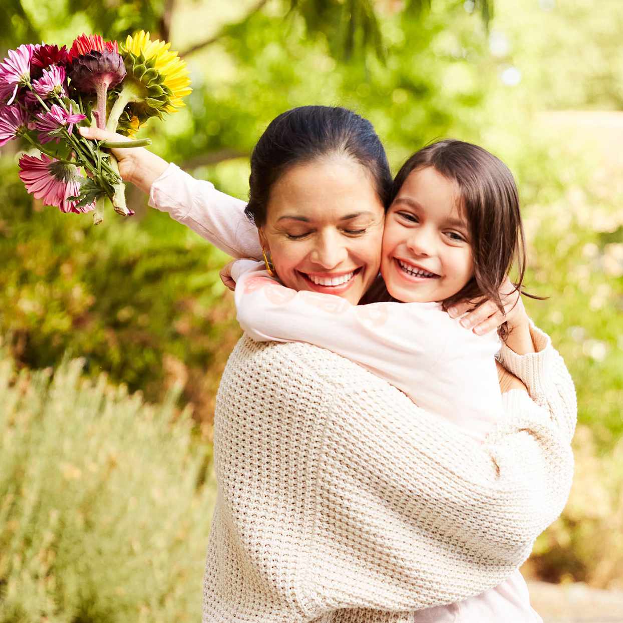 woman hugging child holding flowers