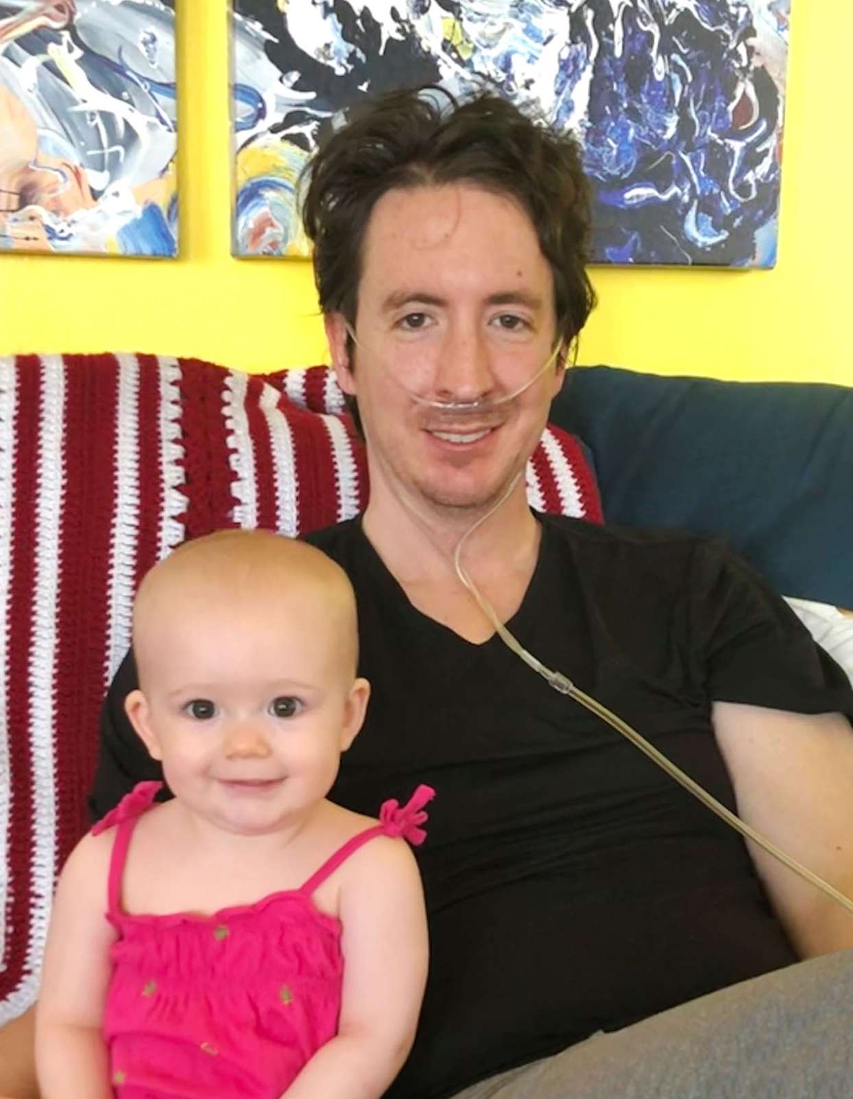 father with oxygen smiling on couch with toddler daughter