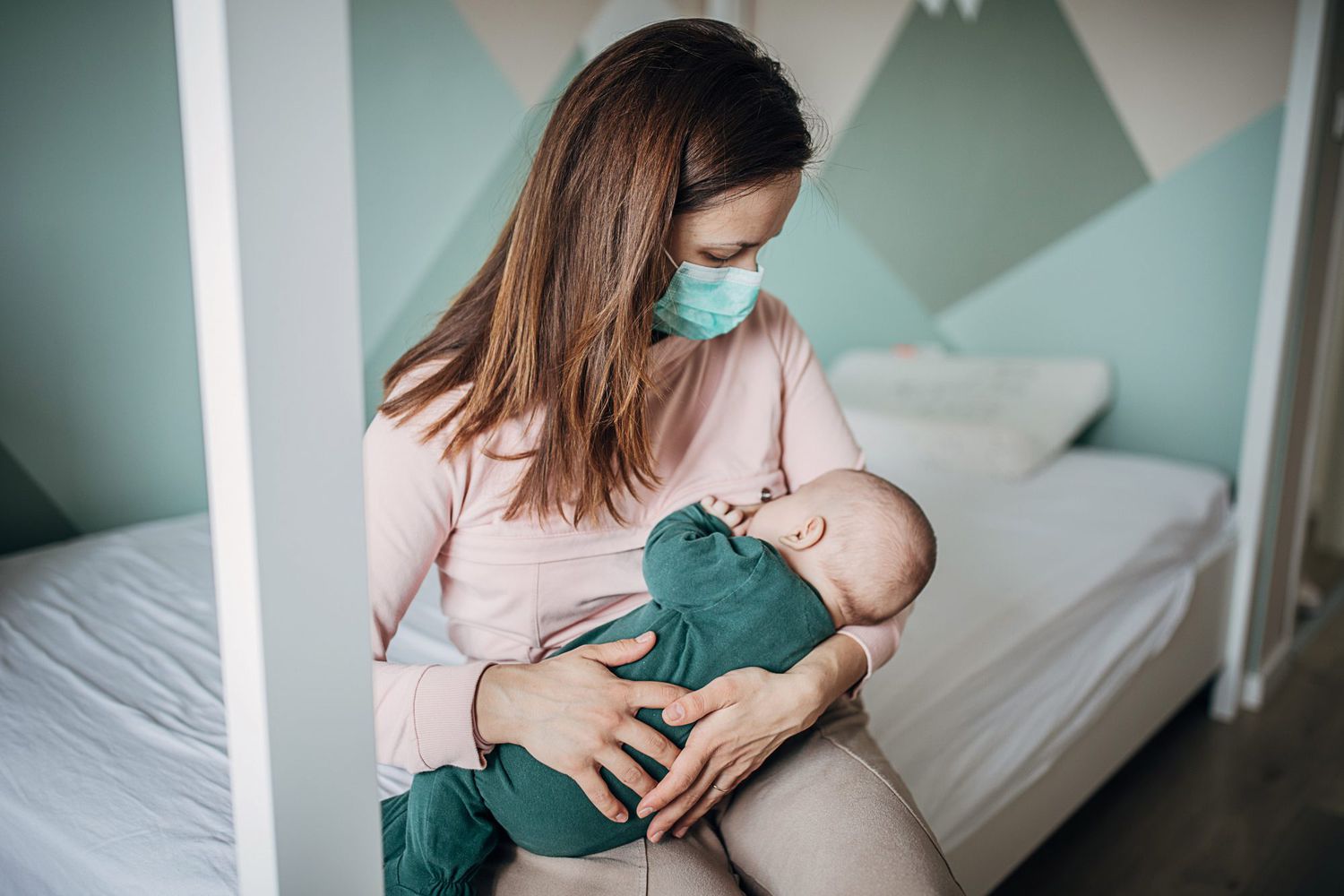 An image of a mother breastfeeding her child in a face mask.
