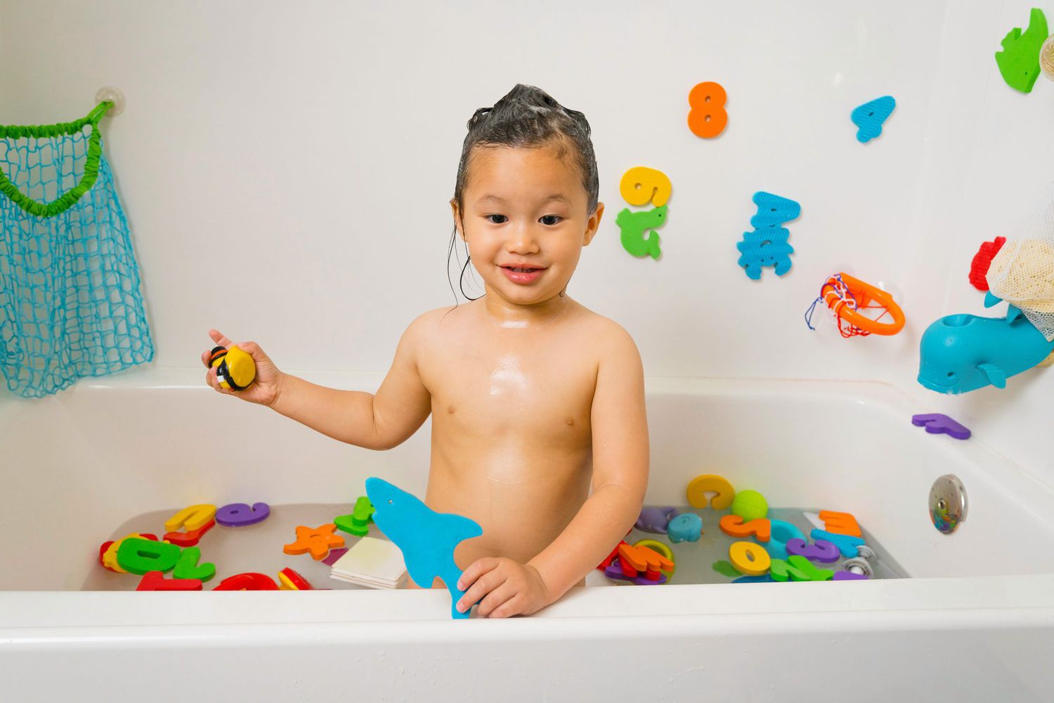 An image of a little boy in a bath tub playing with bath toys.