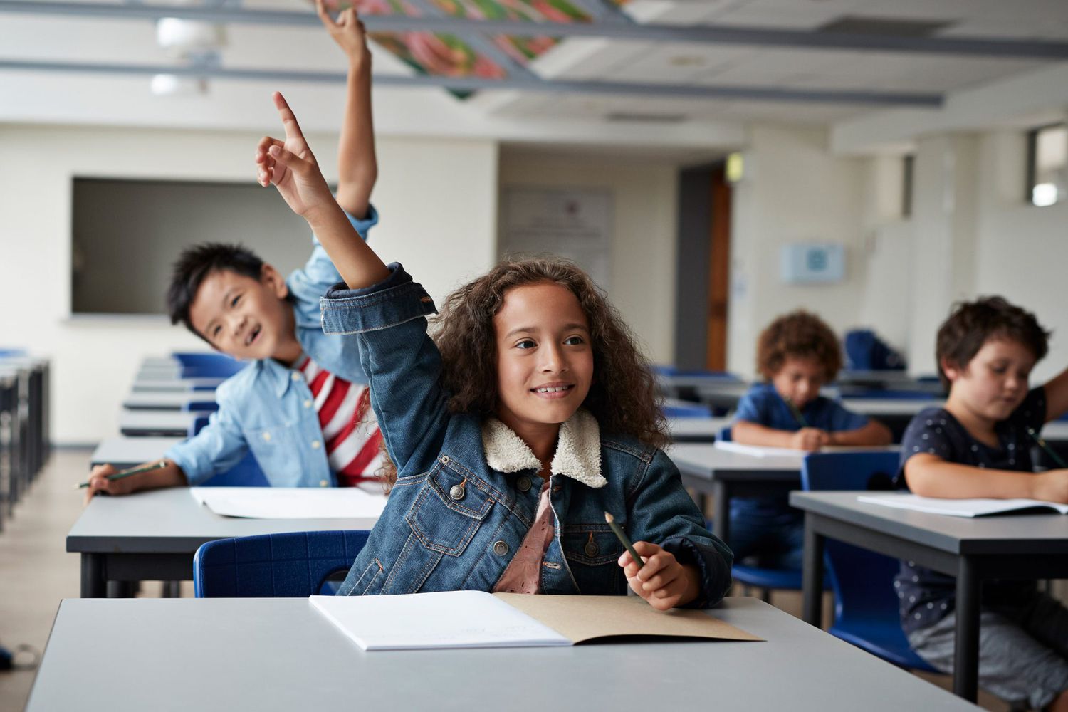 An image of children raising their hands in class.