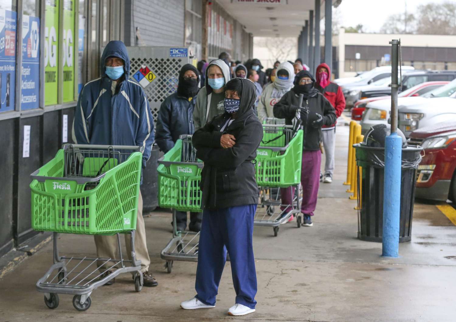 An image of people waiting in line to enter a grocery store in Texas.