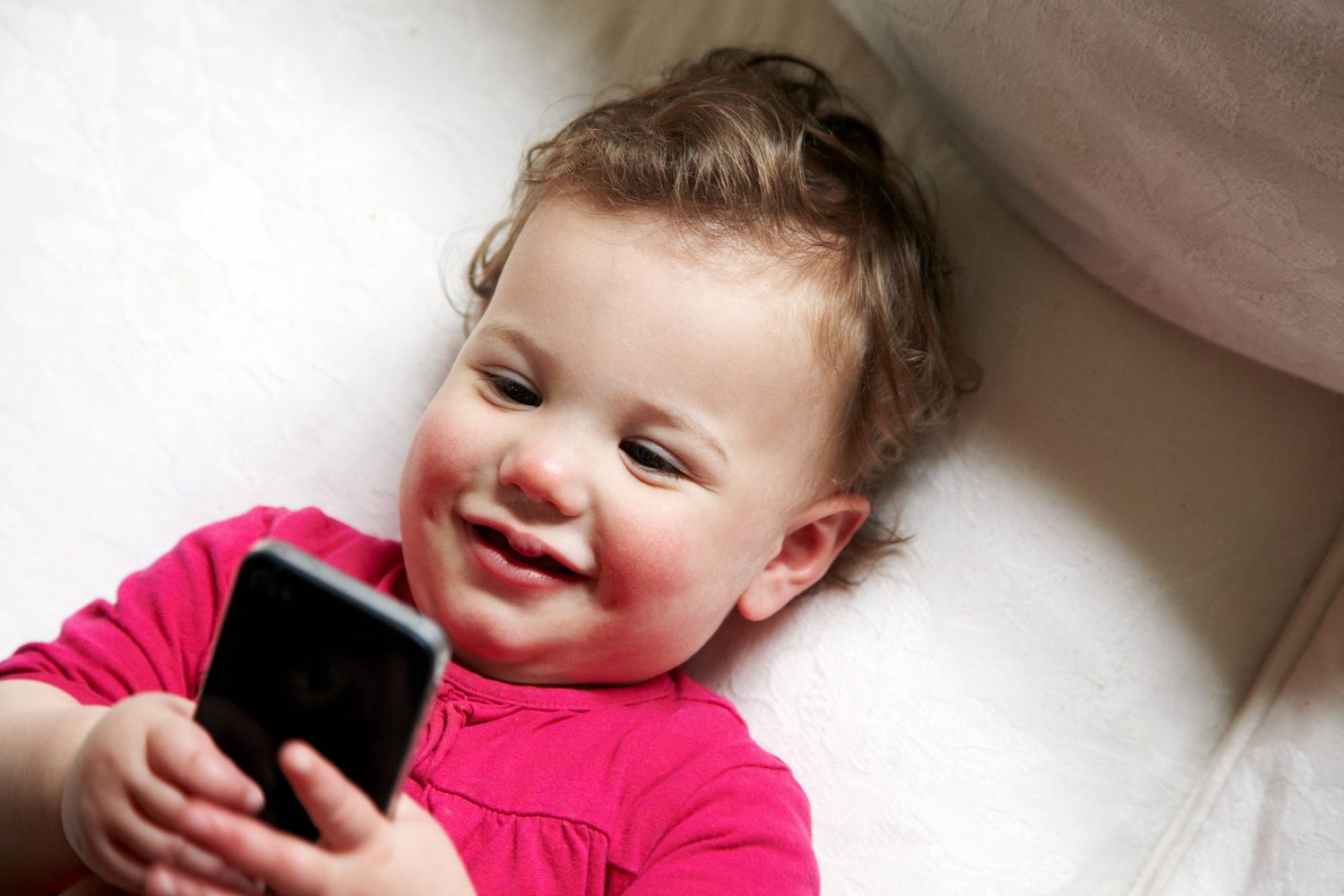 An image of a baby playing on a cellphone.