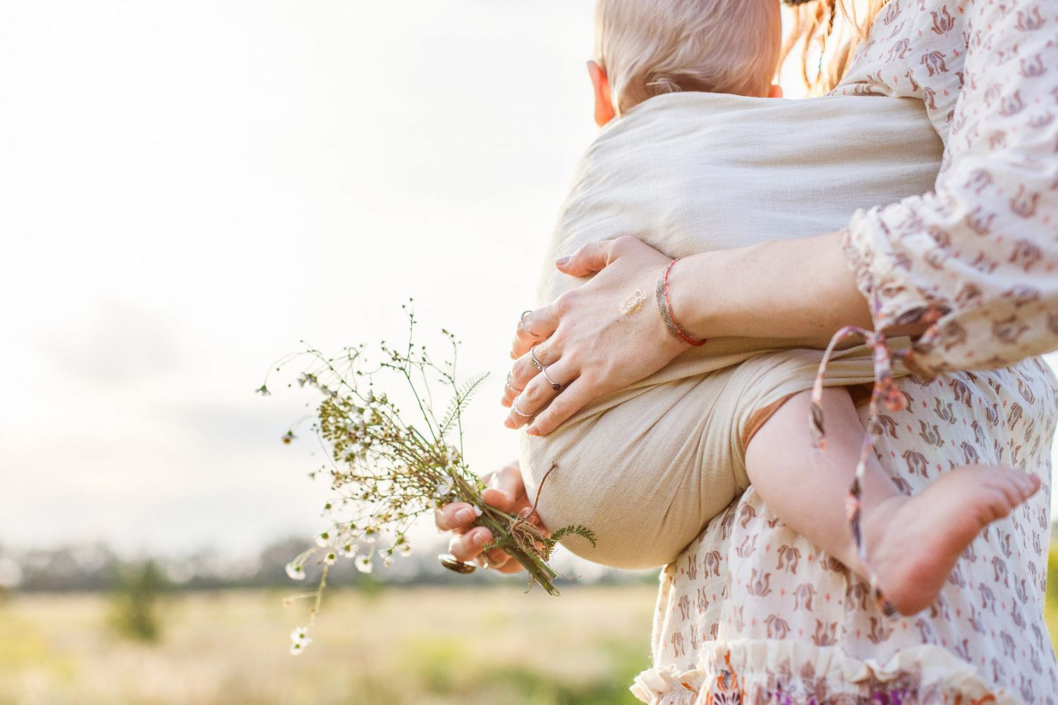 An image of a mom holding her baby in a field.