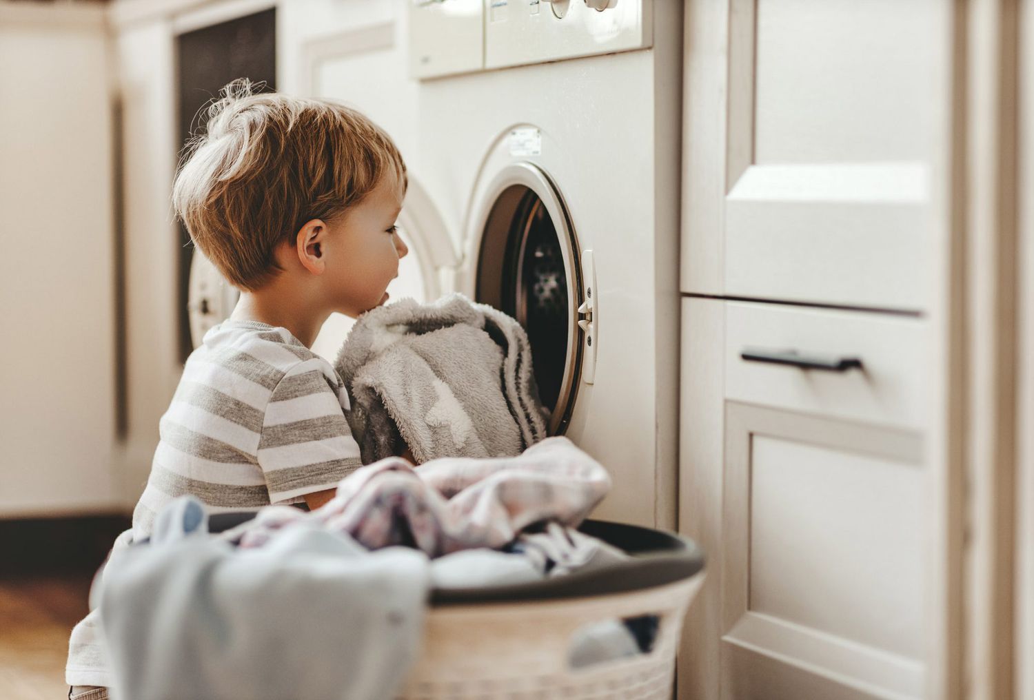 An image of a young boy doing laundry.