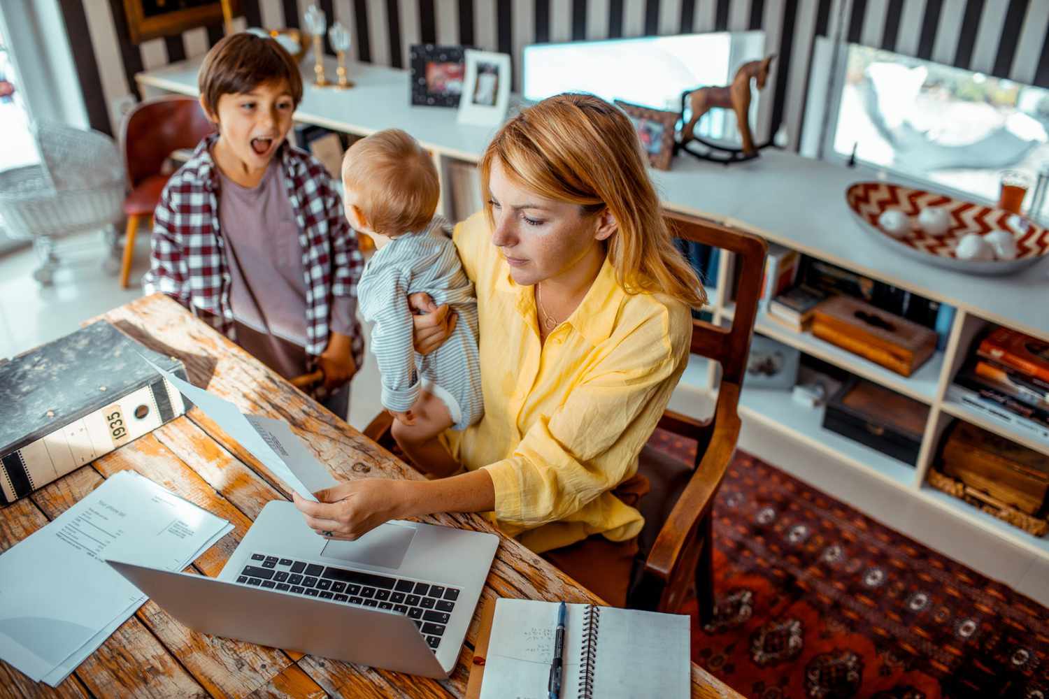 An image of a woman and her children at her desk.