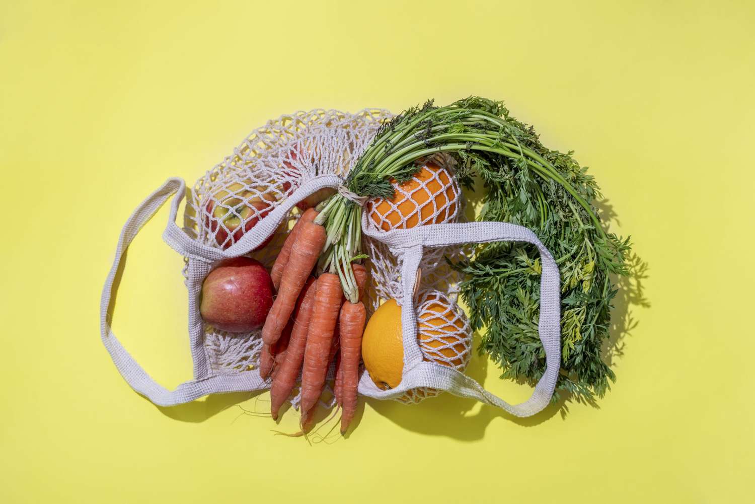 An image of a reusable mesh bag with fruit And vegetables in it.