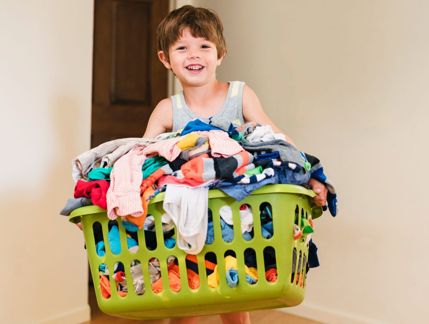 An image of a boy carrying a laundry basket filled with clothes.