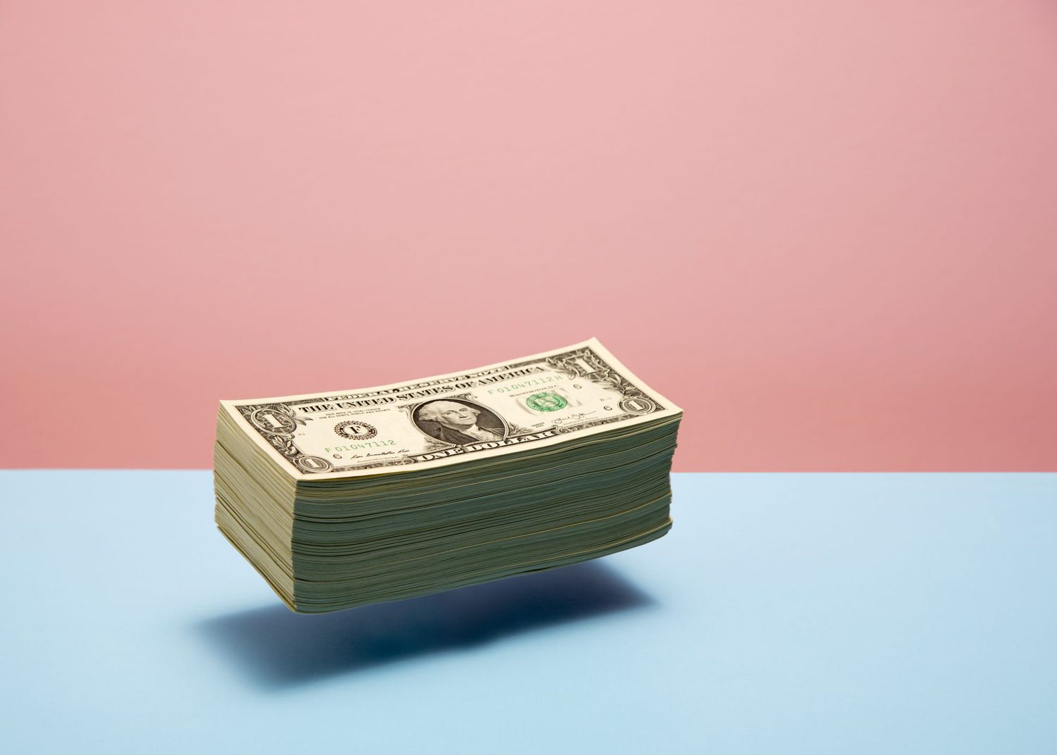 An image of a stack of money floating on a colorful background.