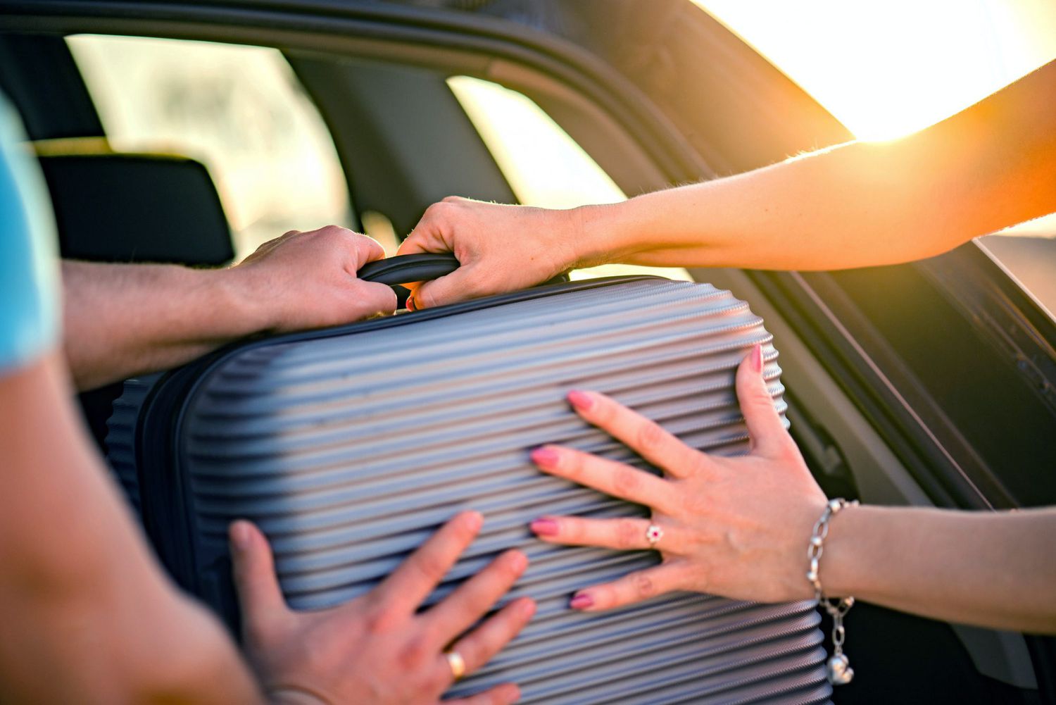 An image of a couple putting luggage in their car.