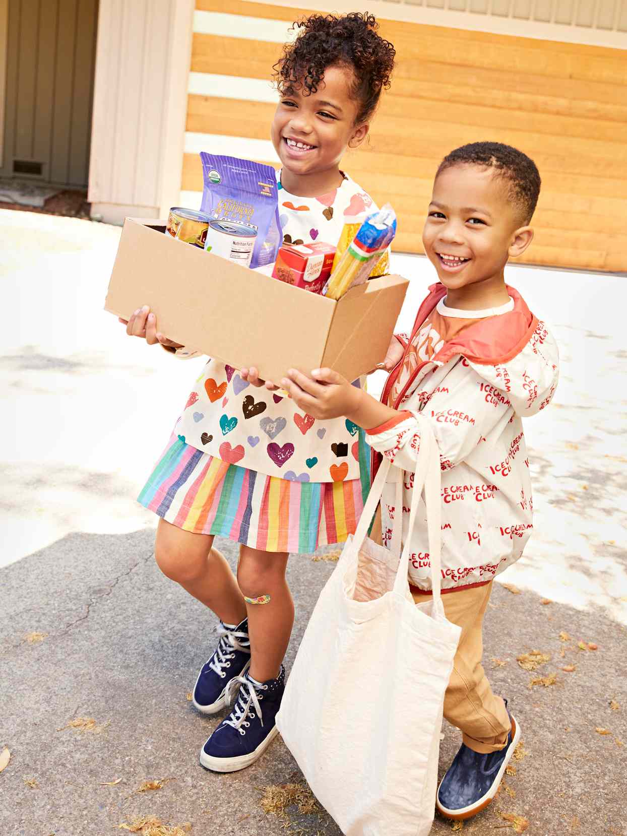 two kids smiling carrying groceries