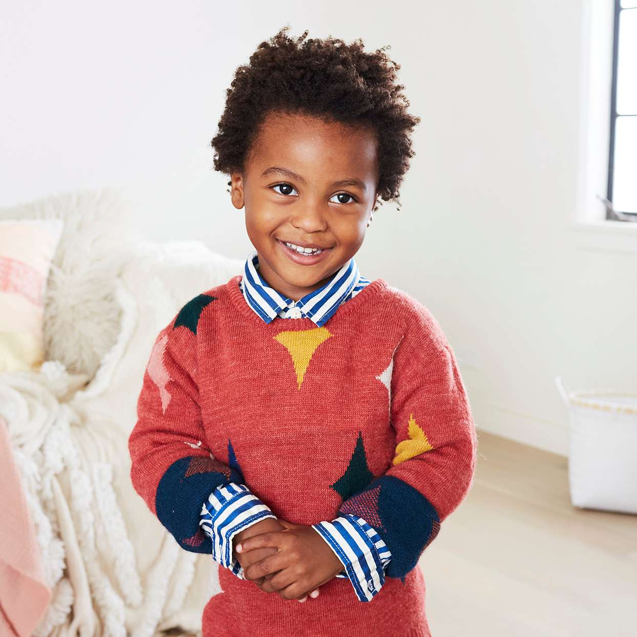 young boy smiling red sweater bedroom