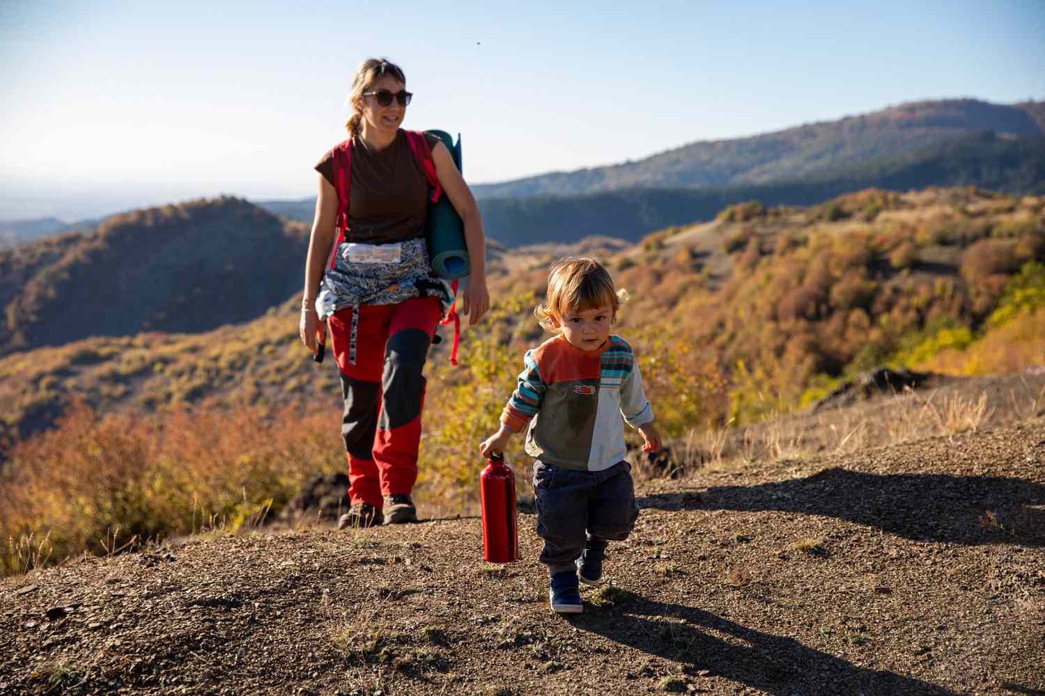 An image of a mom and her child walking in the mountains during autumn.