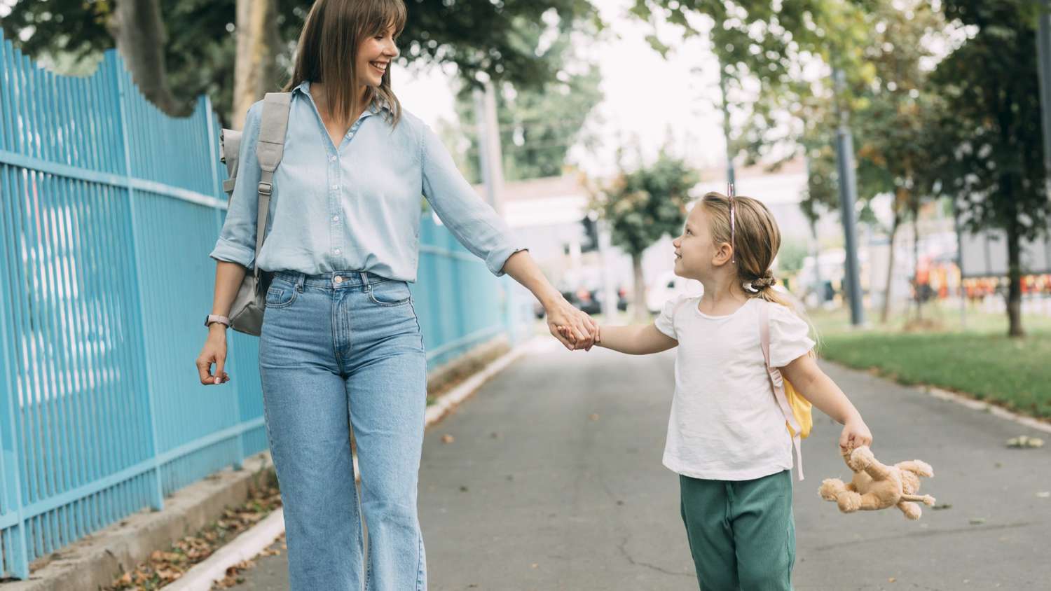 An image of a woman holding her daughter's hand while walking.