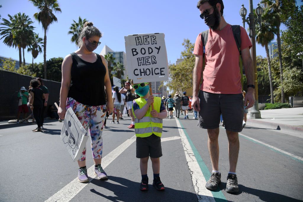 An image of parents with their child holding a sign during a Women's March.