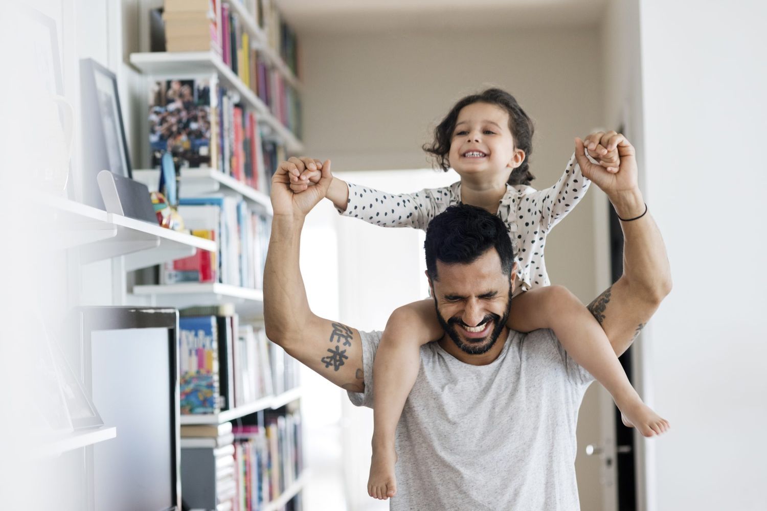 Happy father carrying girl on shoulder while standing at home