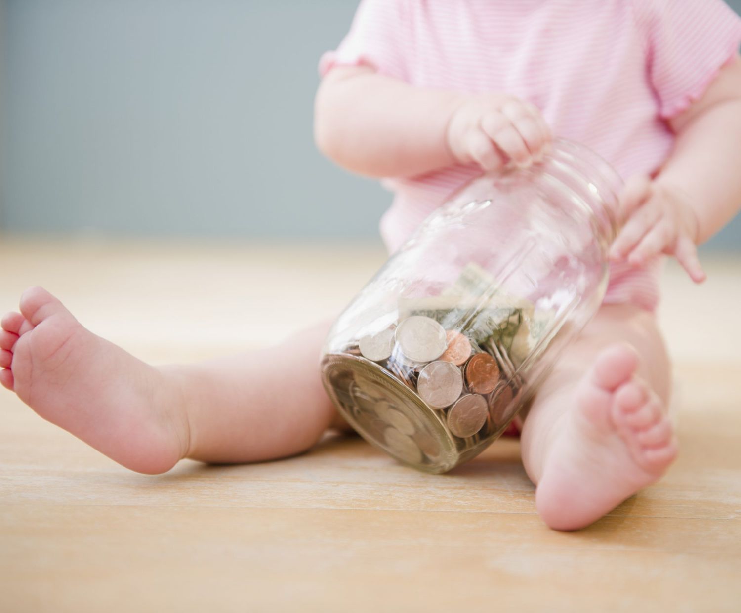 An image of a baby holding a jar with money.