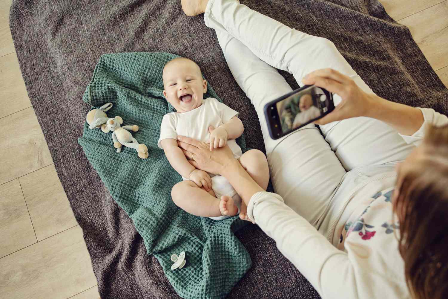 An image of a mom taking a picture of her baby.