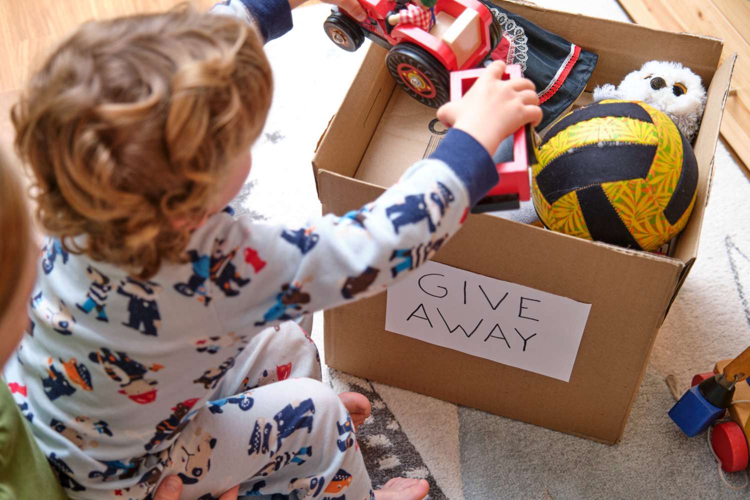 An image of a boy putting toys into a box for donation.