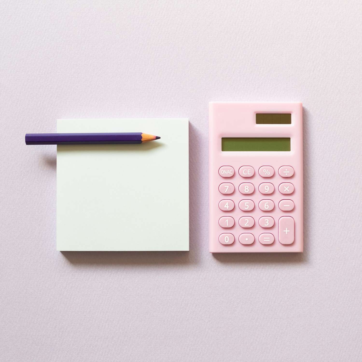 An image of memo paper, sticky notes and digital calculator with colored pencil on pink background.