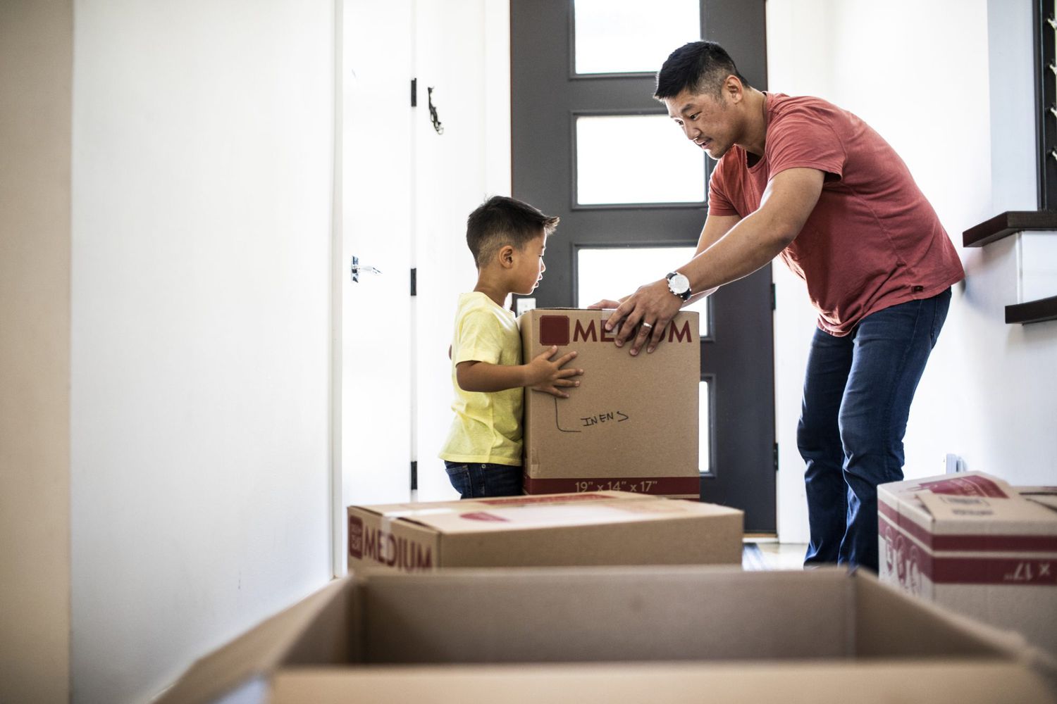 An image of a boy and his dad moving boxes.