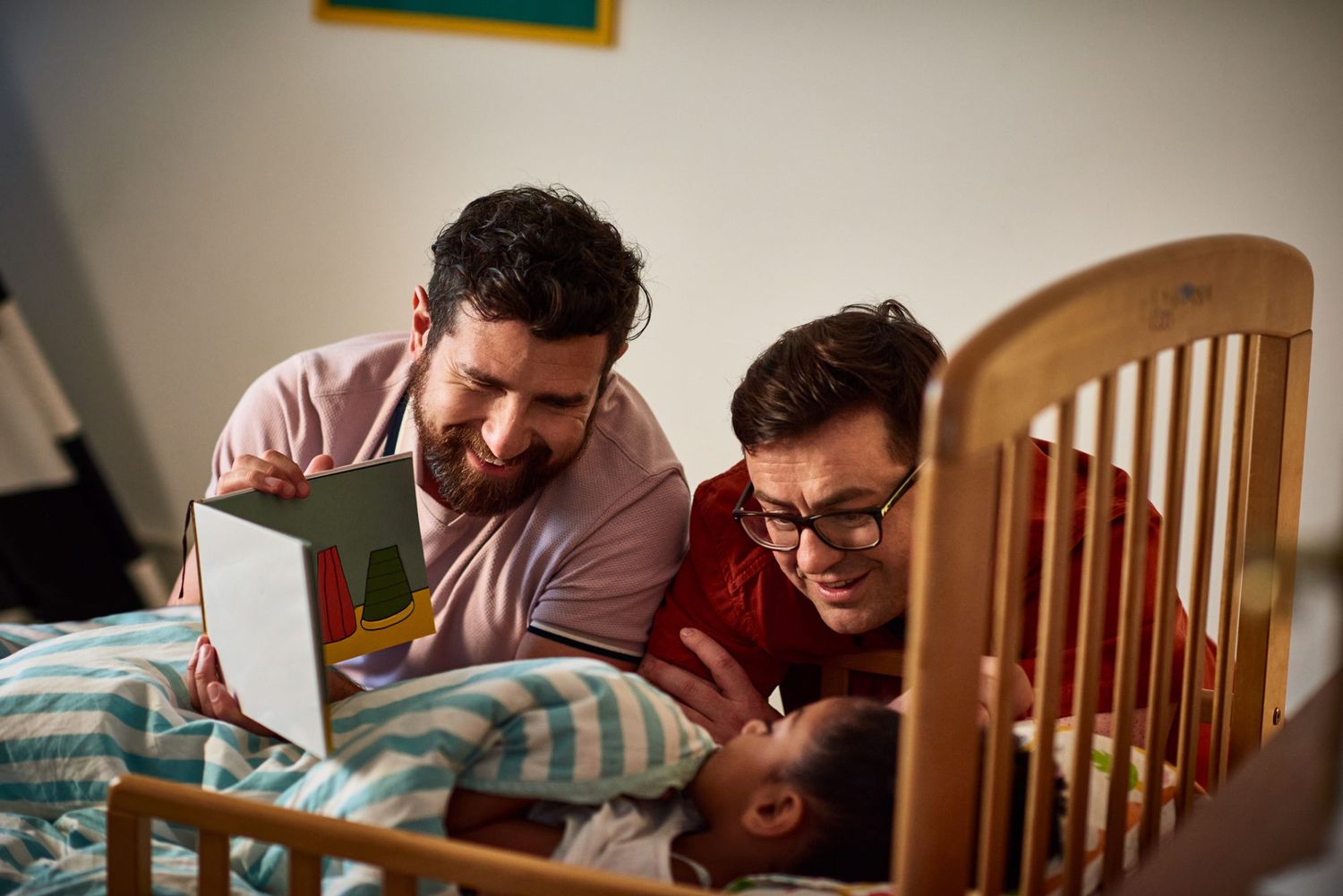 An image of fathers reading a bedtime story to their daughter.