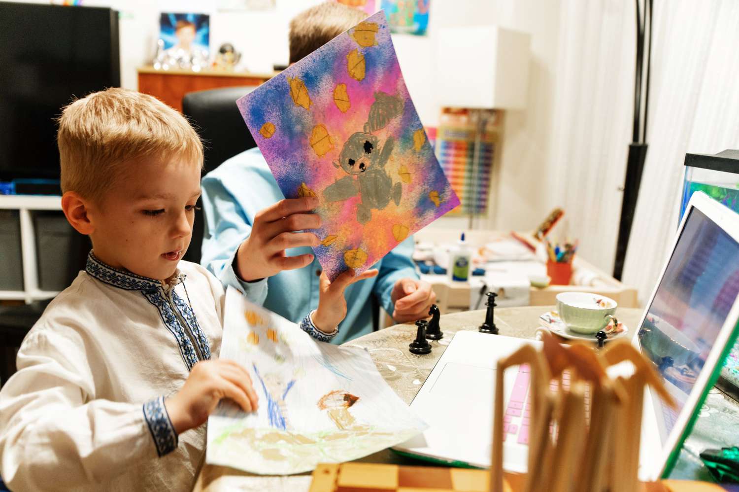An image of Liana Popova's sons showing their artwork during a virtual meeting with Megan.