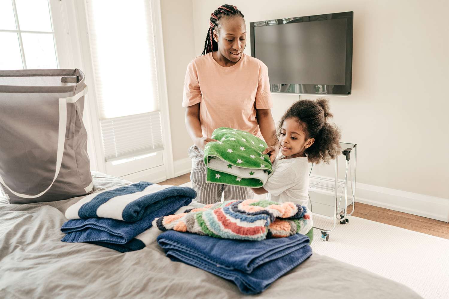 Mom and daughter fold laundry in a bedroom