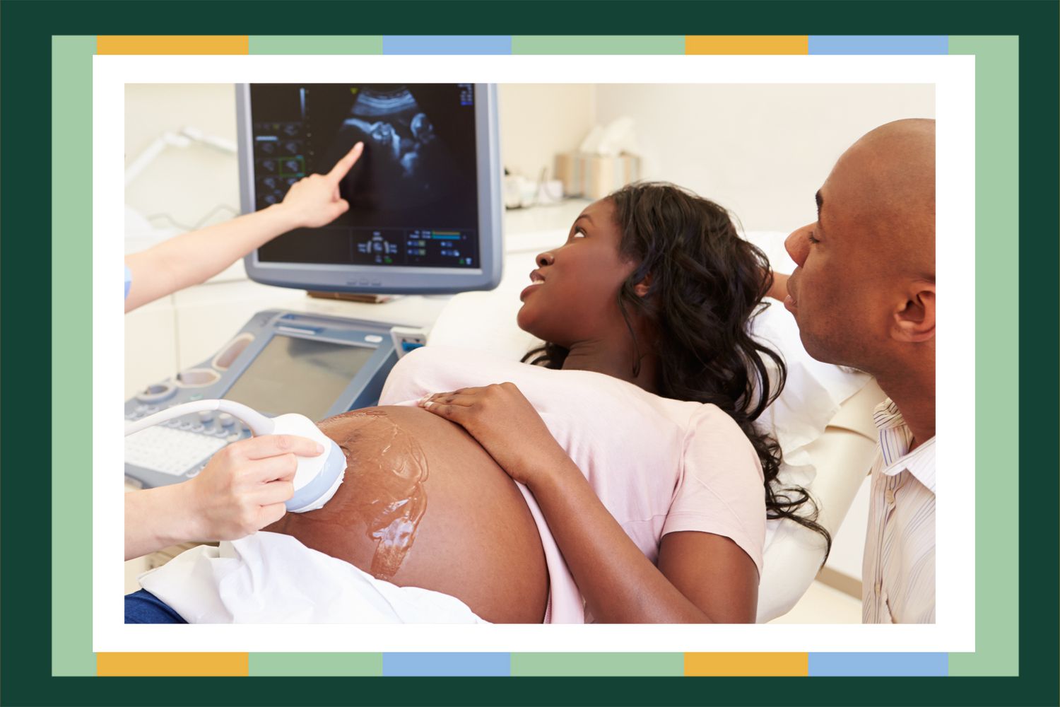 Black pregnant woman receiving ultrasound. She and her husband are viewing the screen.