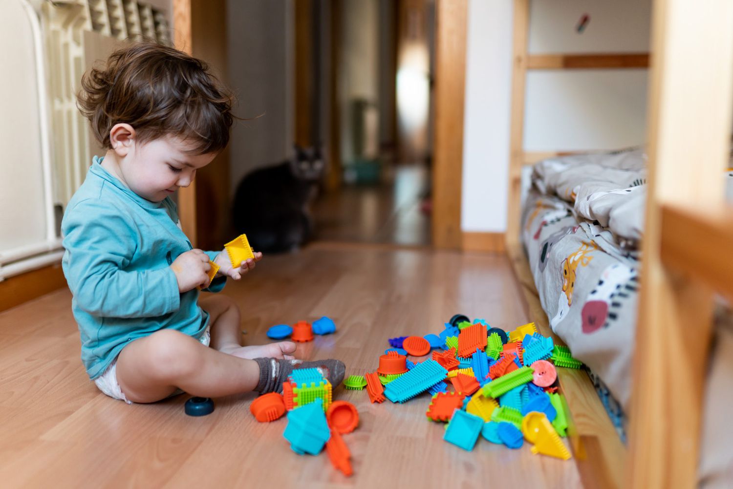 Baby playing at bedroom with colorful construction pieces sittion on the floor
