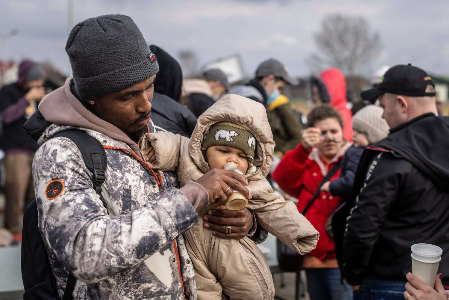 African man holding baby among Refugees at Medyka pedestrian border crossing fleeing the conflict in Ukraine