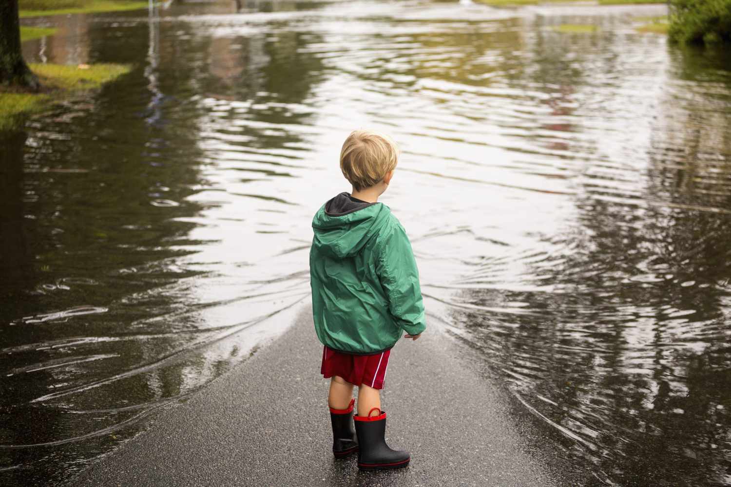 Child standing next to flooded road