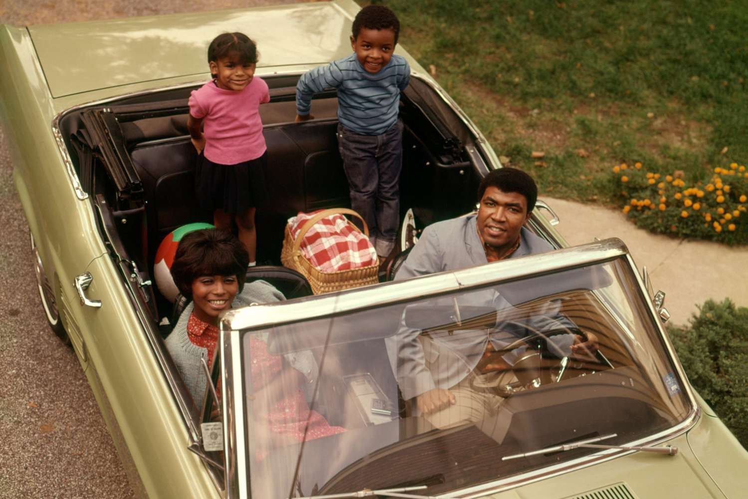 1970s AFRICAN AMERICAN FAMILY OF FOUR SEATED IN CONVERTIBLE CAR FATHER MOTHER SON DAUGHTER LOOKING AT CAMERA