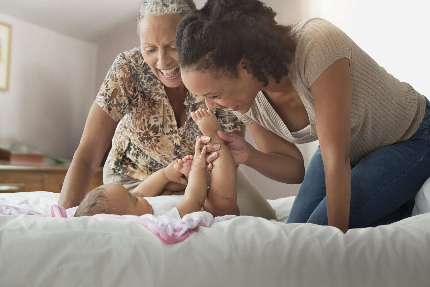 Three generations of women playing on bed
