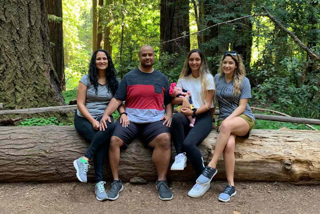 Family sits on a fallen tree in a park