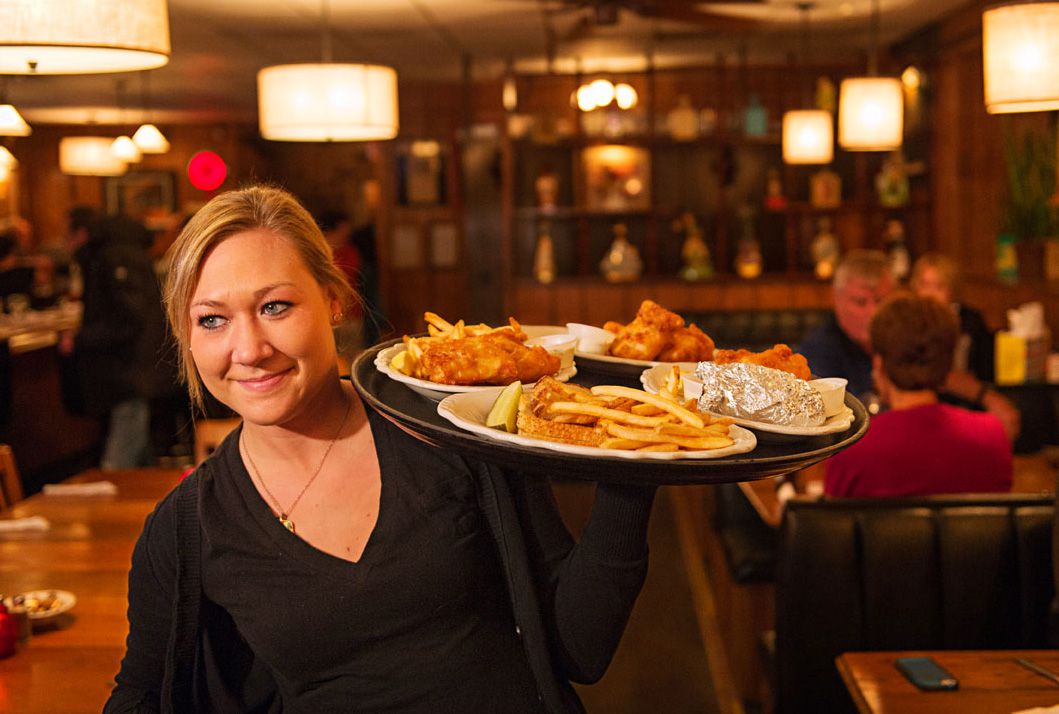 A waitress serves platters of fish at Avenue Bar.