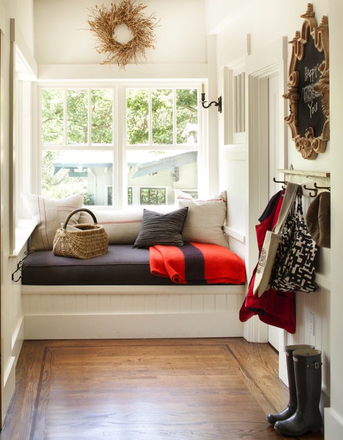 A white mudroom with a cozy window bench.
