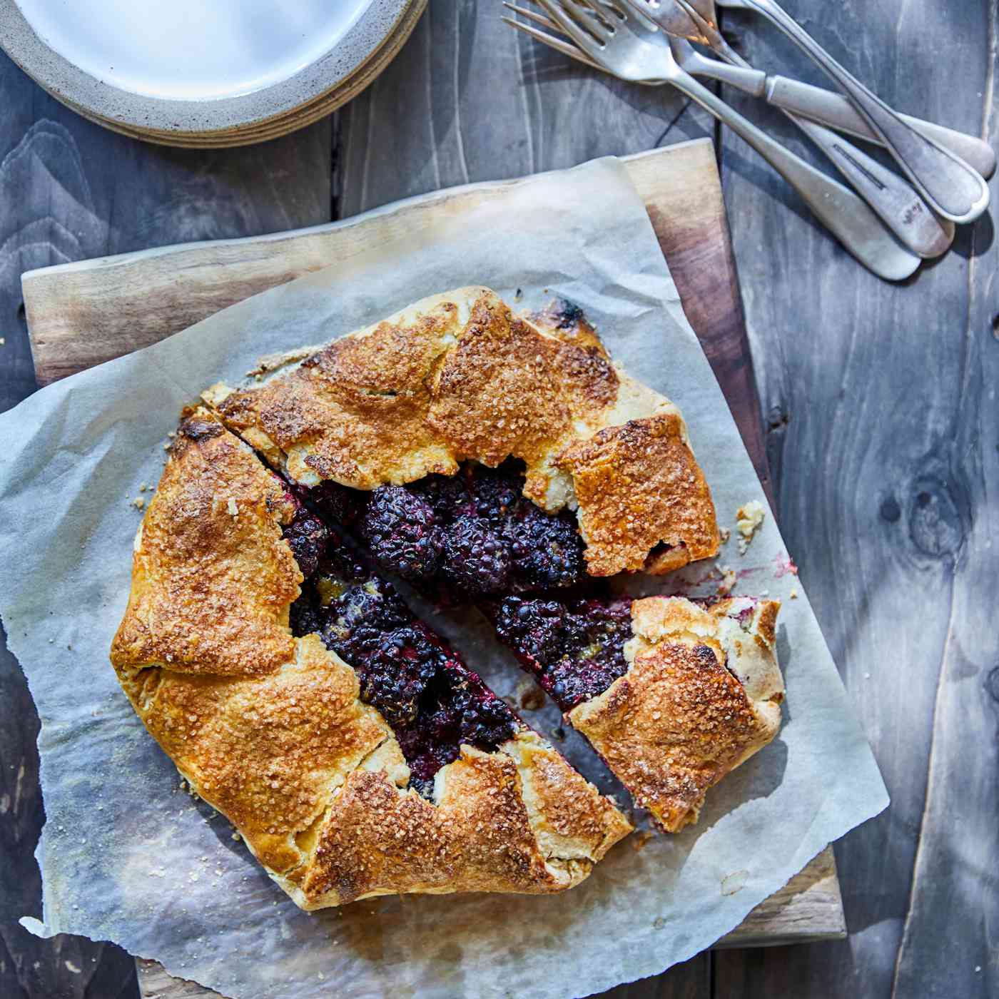 wooden table with Blackberry Galette on parchment paper