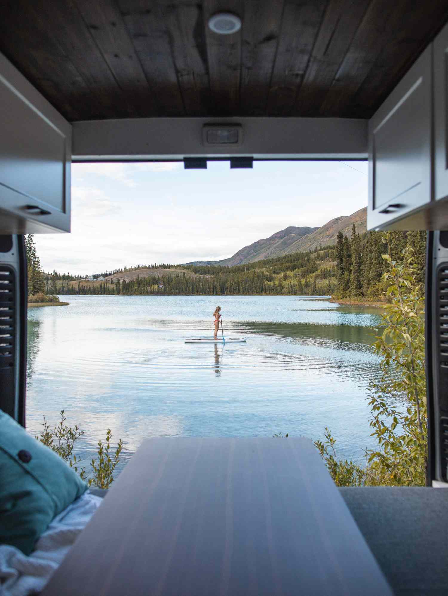 View through RV camper of woman paddleboarding