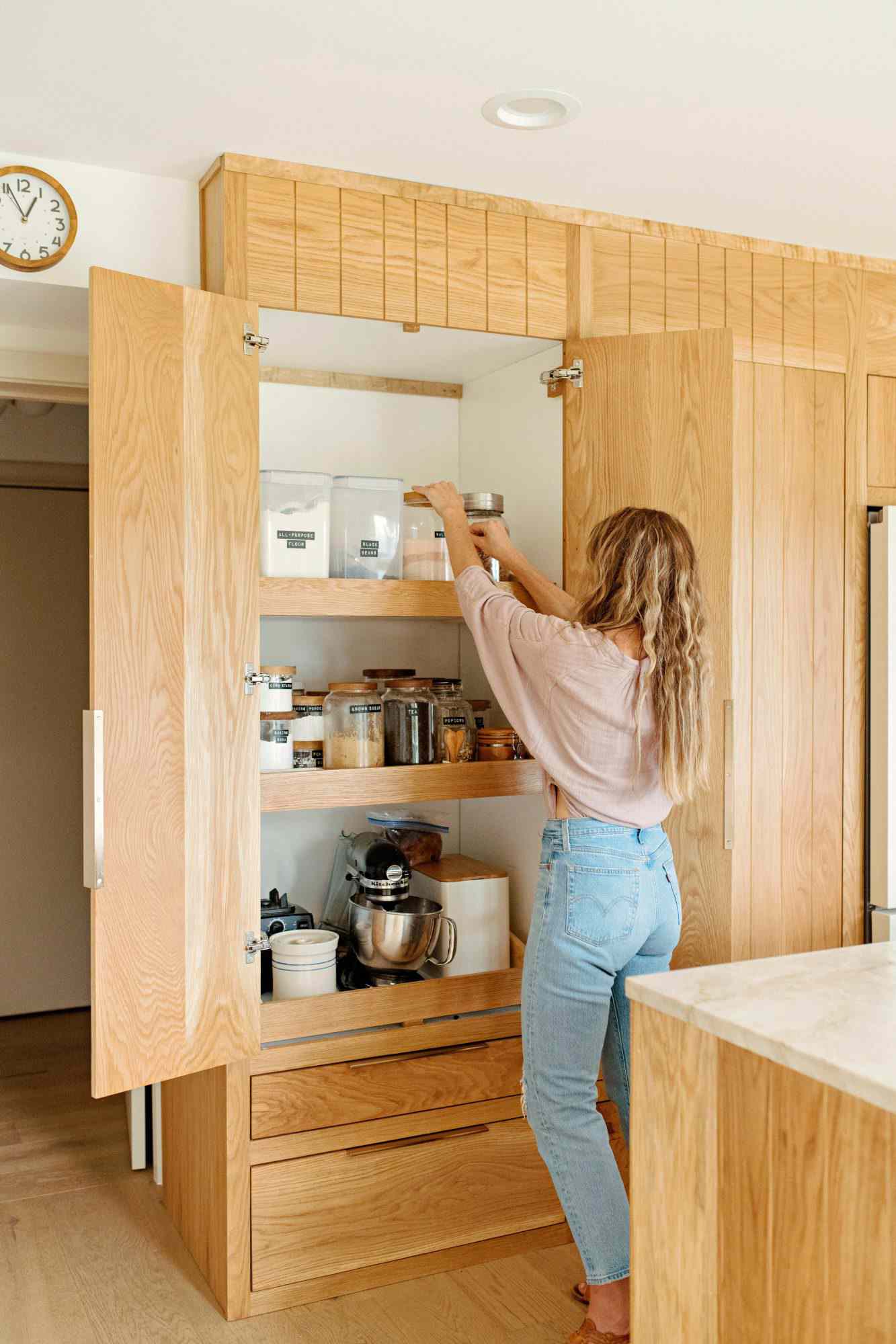 Woman in Mockabee kitchen reaching into pantry